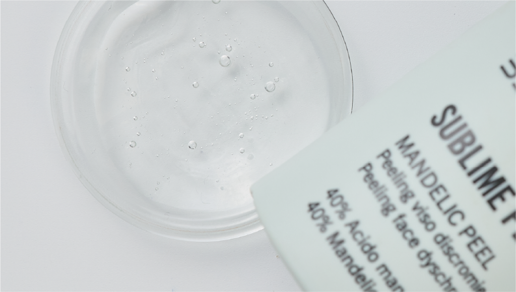 Dettaglio della texture trasparente del peeling viso Sublime Peel Mandelic Peel Beautech, con microbolle visibili e packaging in primo piano su sfondo bianco.
