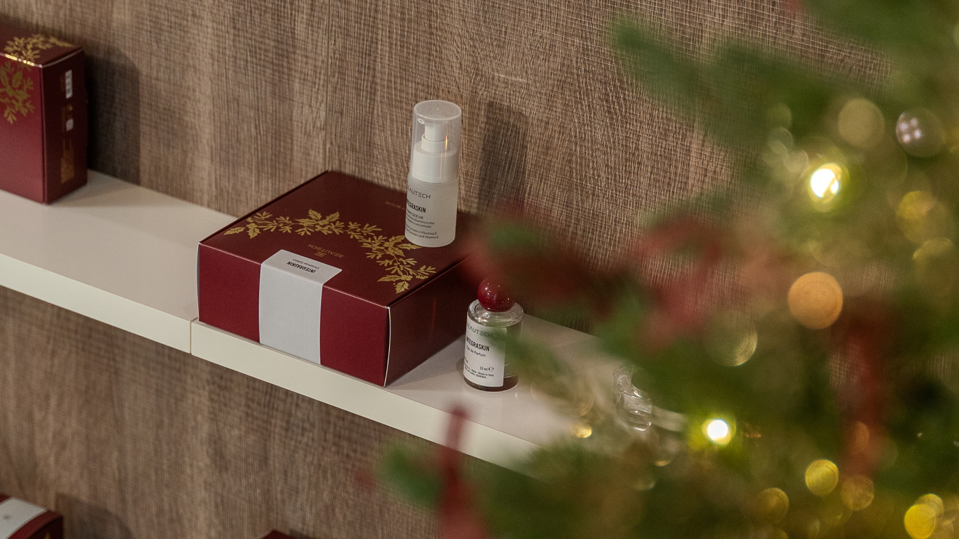 Cofanetto regalo natalizio Beautech Integraskin con siero viso e profumo Scent Vibe, esposto su una mensola bianca tra decorazioni natalizie e luci calde.